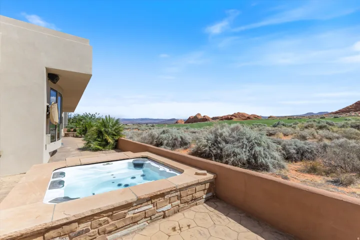 Private patio with an integrated spa, stone-clad surround, and stamped concrete flooring