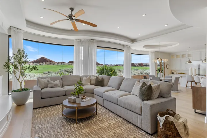 Expansive living area with curved floor-to-ceiling windows, wood-finish flooring, and recessed lighting