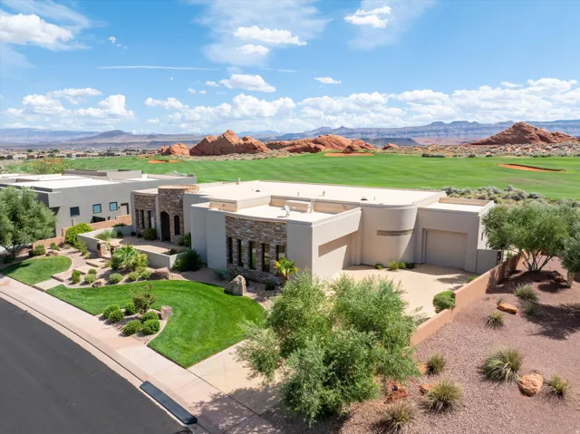 Desert-contemporary residence with stone accents, a multi-level flat roof, and an attached garage
