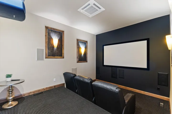Dedicated media room featuring a large projection screen, dark accent wall, and built-in wall speakers