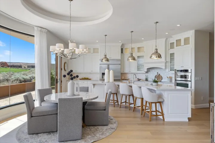 Gourmet kitchen with white cabinetry, stainless steel appliances, and a central island with bar seating