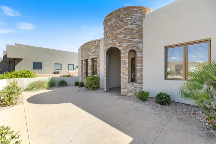 Stucco exterior with stone veneer accents, arched entry, and desert landscaping