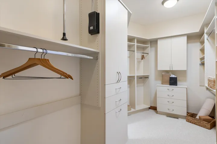 Built-in closet organization system with multiple hanging rods, shelving, and drawer units
