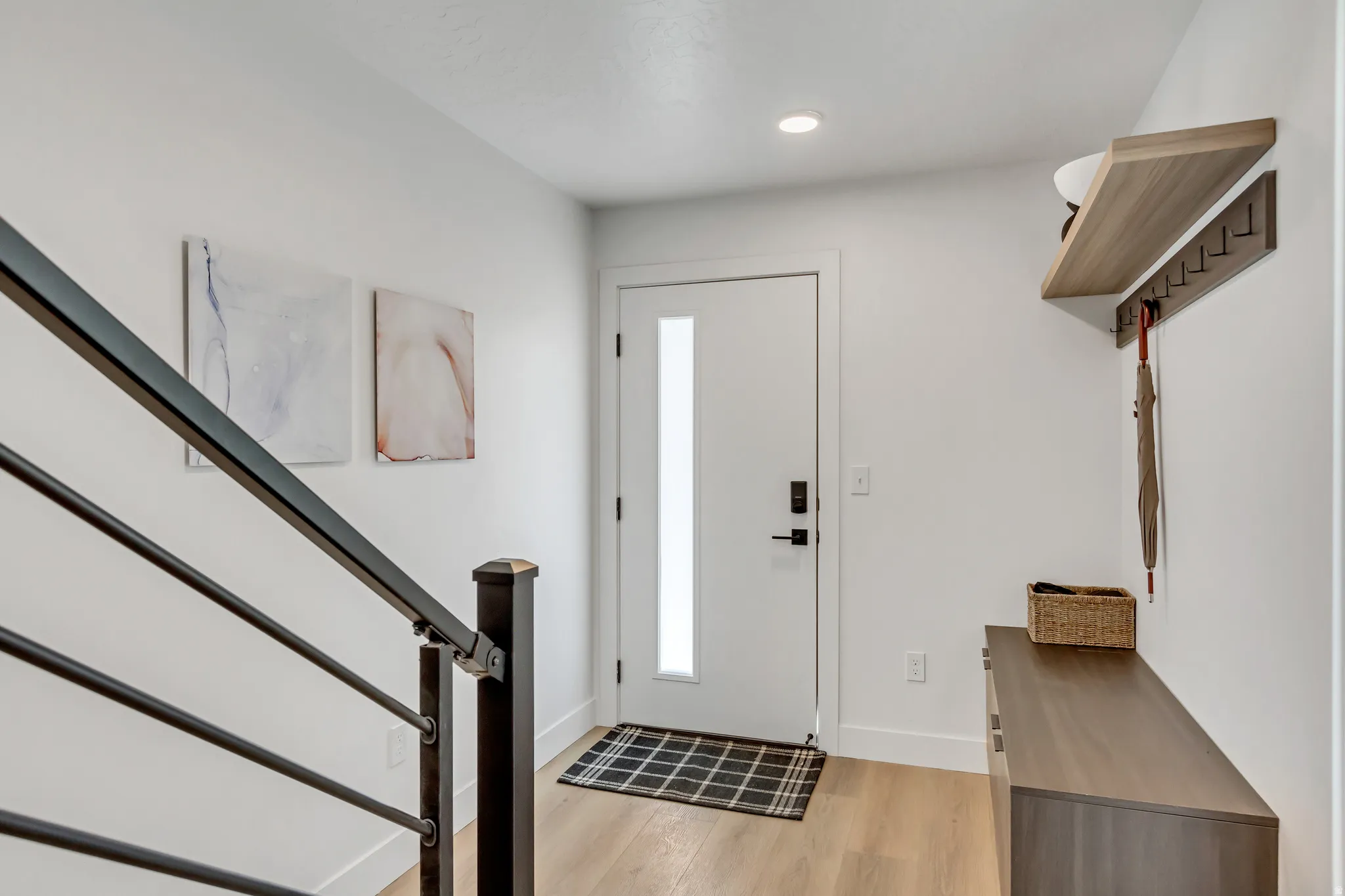 Entryway featuring wood-finish flooring, a contemporary white door with frosted glass, and a built-in wood-look shelf with integrated hooks