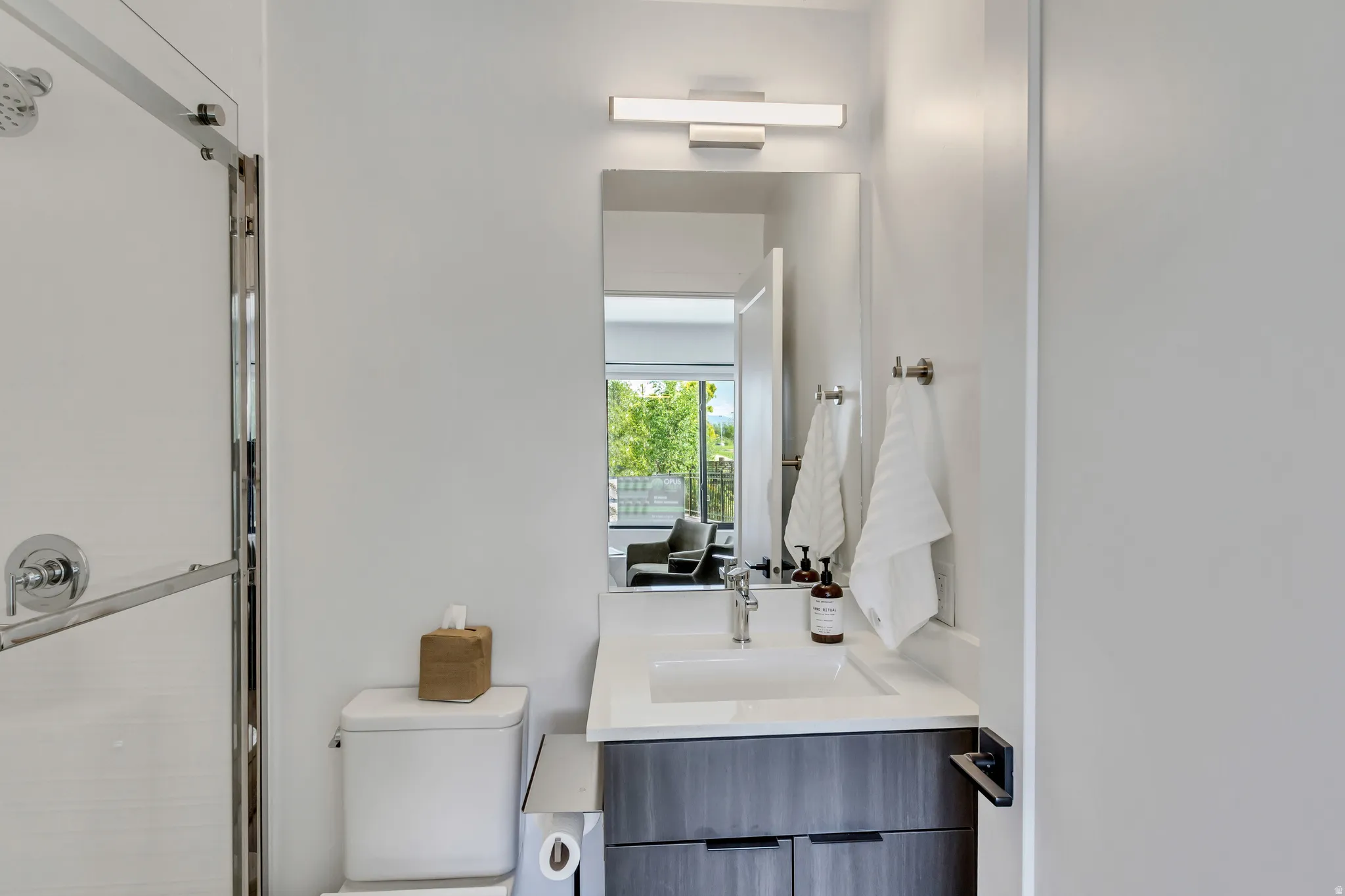 Bathroom featuring a contemporary vanity with an integrated sink, white countertop, and a wood-finish cabinet
