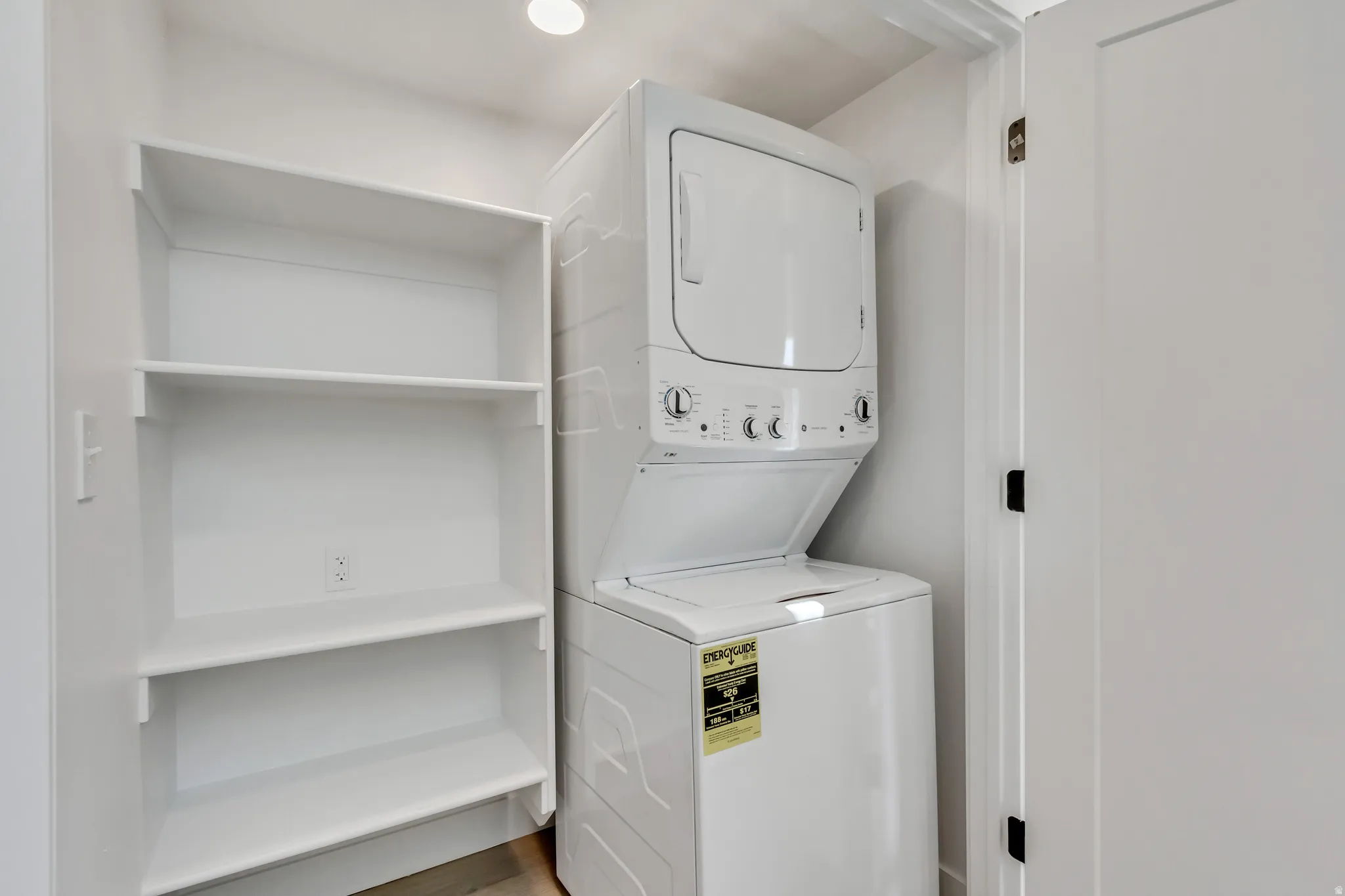 Stackable washer and dryer within a dedicated utility space, featuring built-in shelving