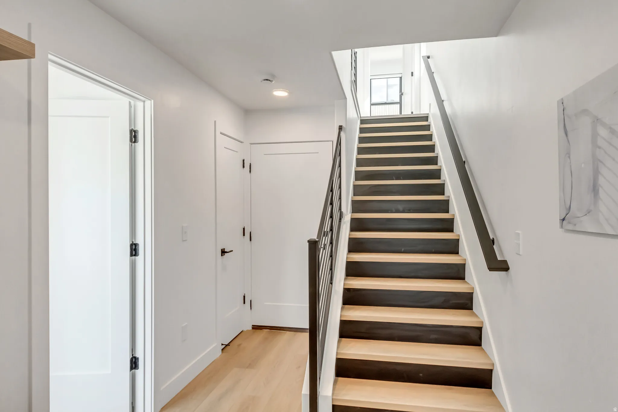 Contemporary staircase featuring a dark metal railing and wood-finish treads