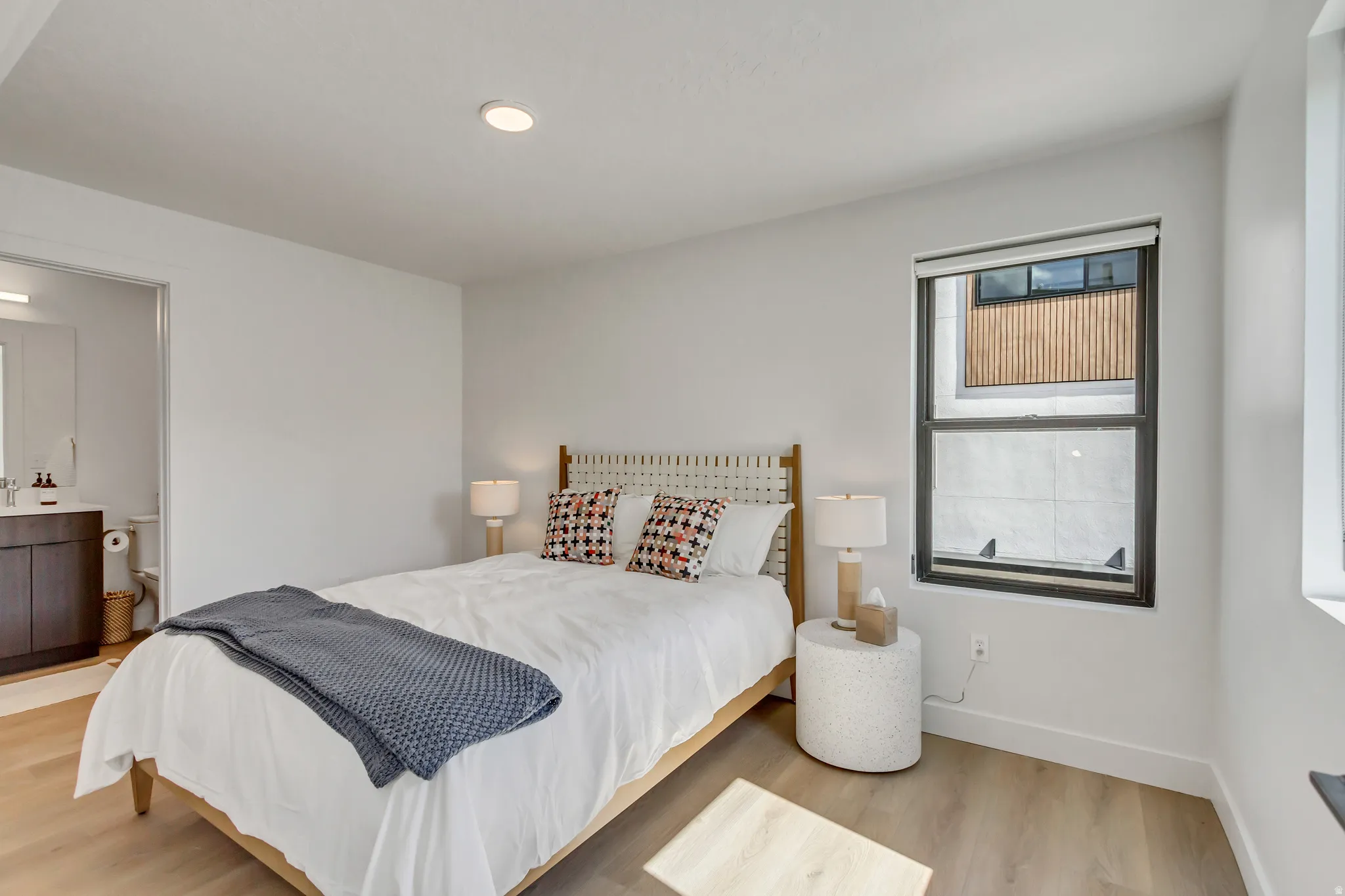Recessed ceiling lighting, wood-finish flooring, and a large window with roller shades