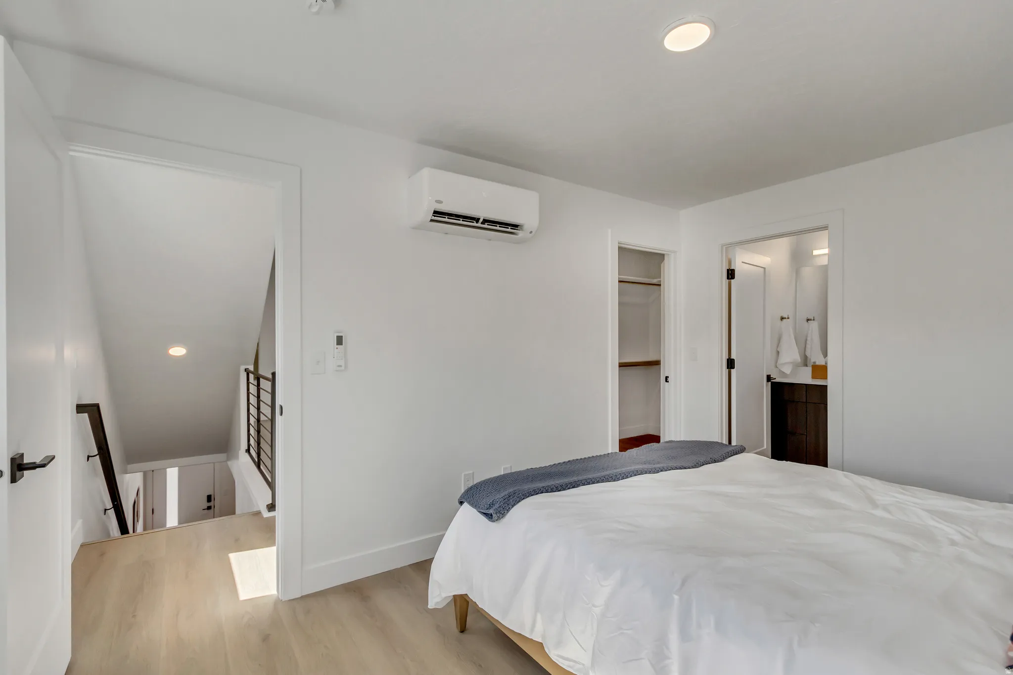 White walls with recessed lighting, wood-finish flooring, built-in closet shelving, and a dark wood-finish vanity with a vessel sink