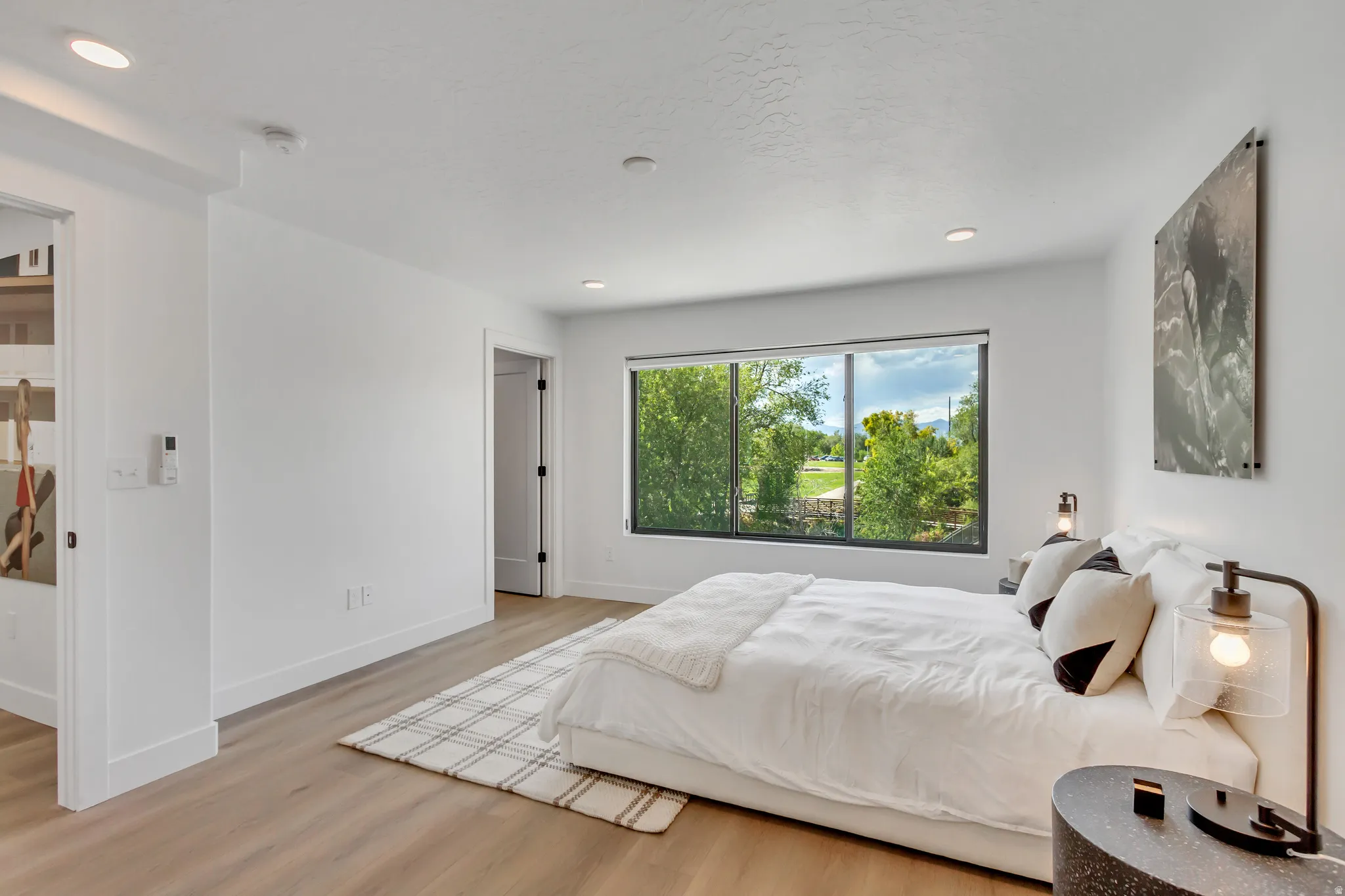 Wood-finish flooring, recessed lighting, and a large window with a black frame