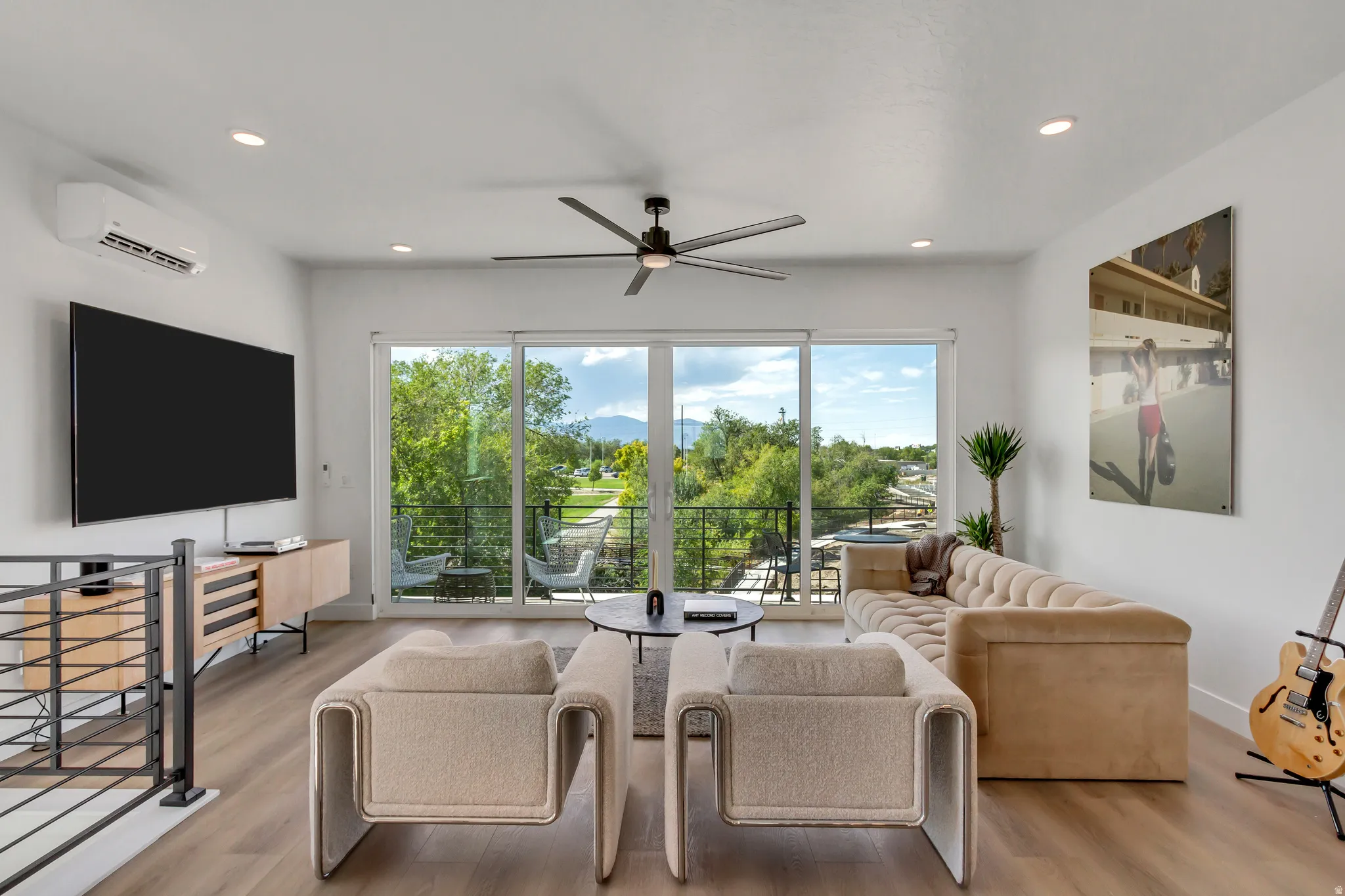 Expansive sliding glass doors, wood-finish flooring, recessed lighting, and a modern ceiling fan