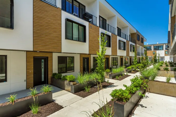 Modern exterior design featuring wood-finish siding, white stucco, and black-framed windows