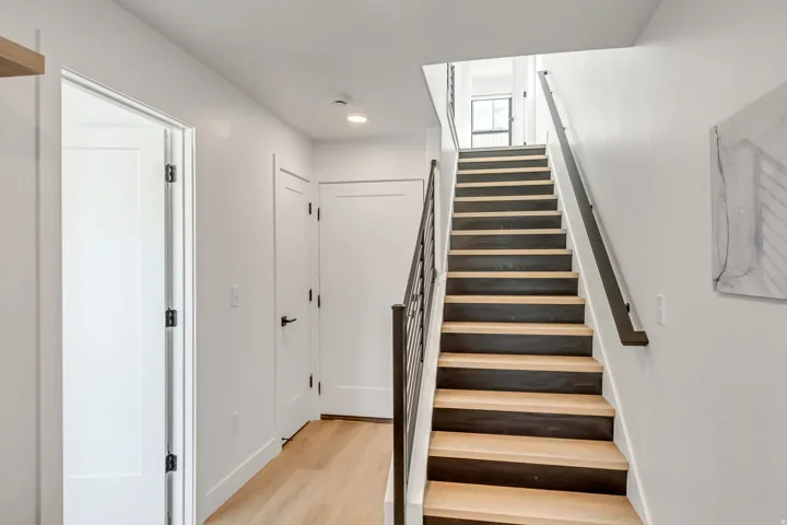 Contemporary staircase featuring a dark metal railing and wood-finish treads