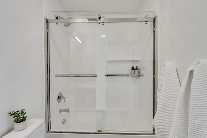 Sliding glass shower enclosure with chrome hardware and integrated showerhead