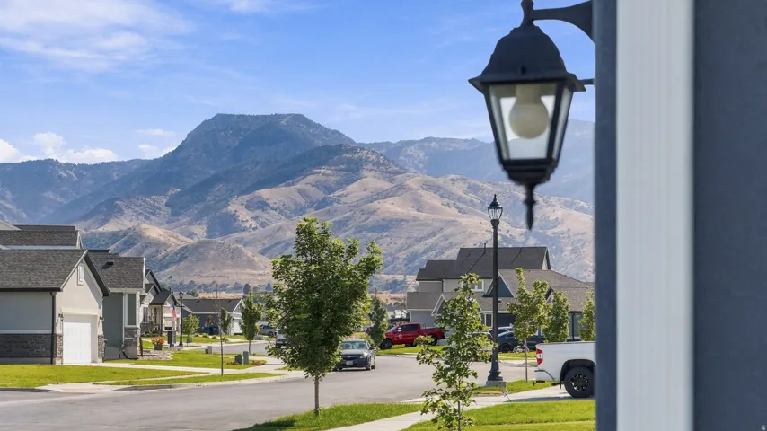 Neighborhood street with established street lighting, residential properties, and distant mountain scenery