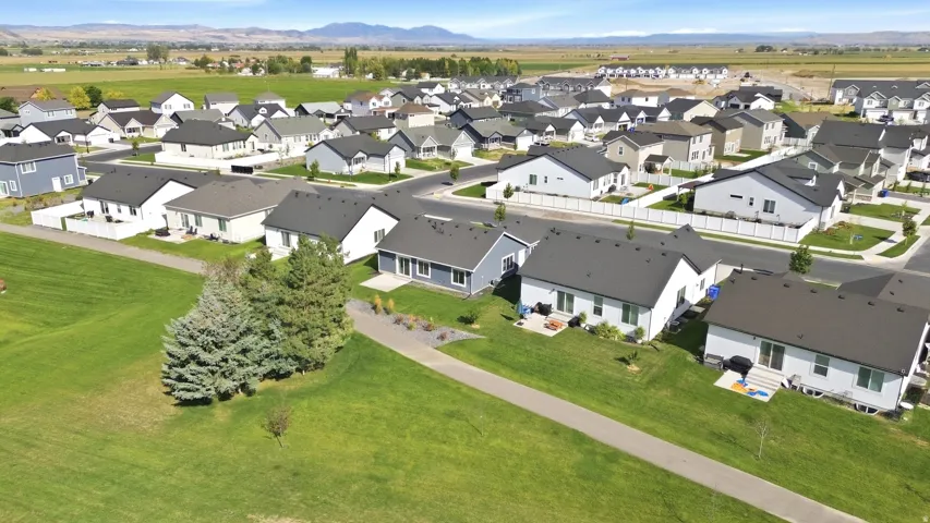 Community setting with a paved path, expansive green spaces, and a mountainous backdrop