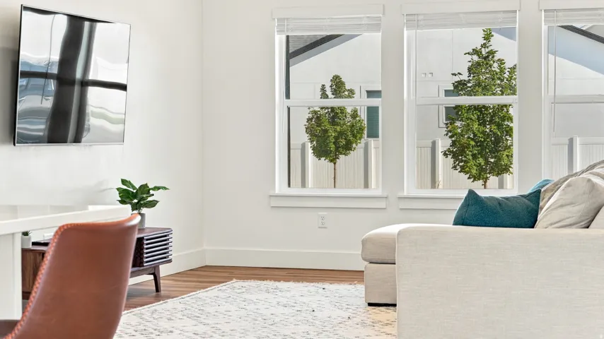 Wood-finish flooring with white baseboards and multiple large windows