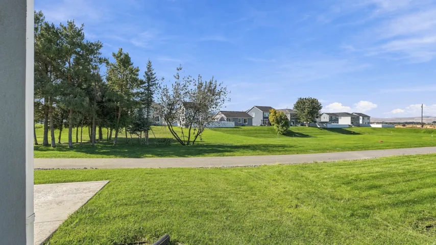 Expansive green space featuring a paved pathway and mature trees