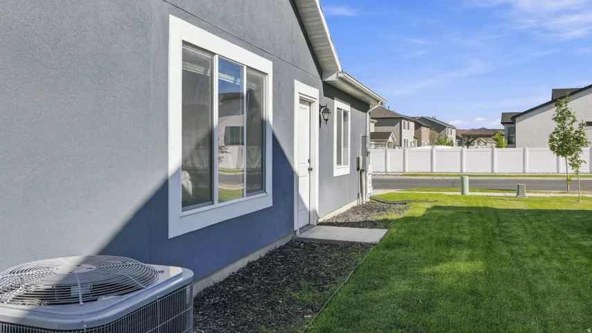 Exterior features include a stucco finish, white frame windows, a side door entry, and a manicured lawn