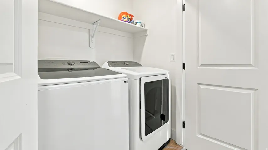 Dedicated laundry space featuring white paneled doors, a wall-mounted shelf, and light wood-finish flooring