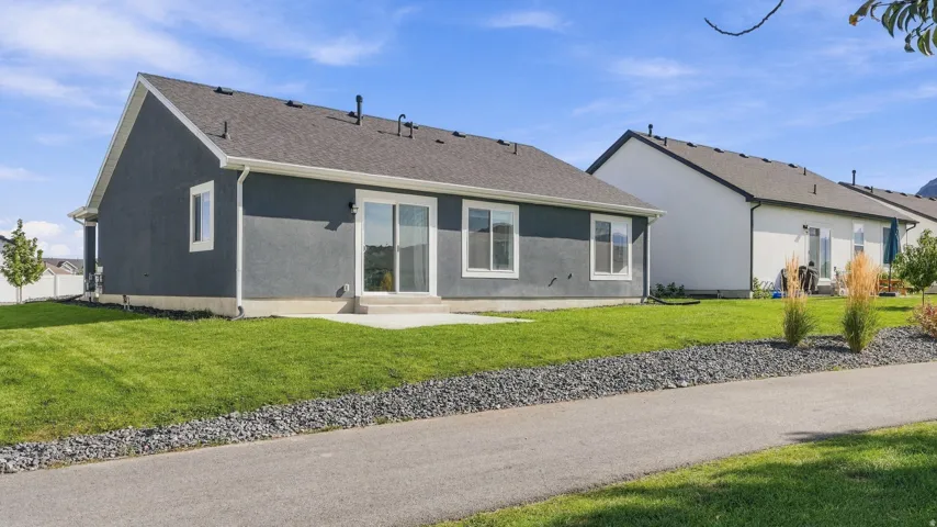 Rear exterior featuring a concrete patio, sliding glass door, and a well-maintained lawn
