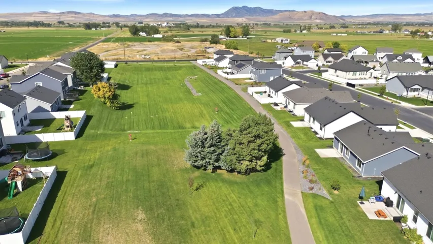 Expansive green space with distant mountain backdrop, surrounded by residential properties and agricultural fields