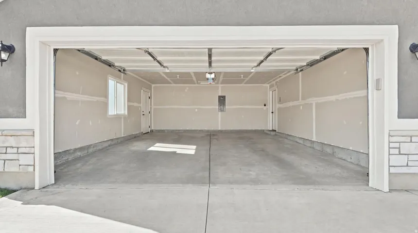 Spacious garage with unfinished walls, concrete flooring, and an exterior stone accent
