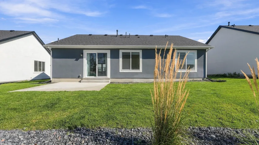 Expansive backyard featuring a manicured lawn, concrete patio, and a sliding glass door