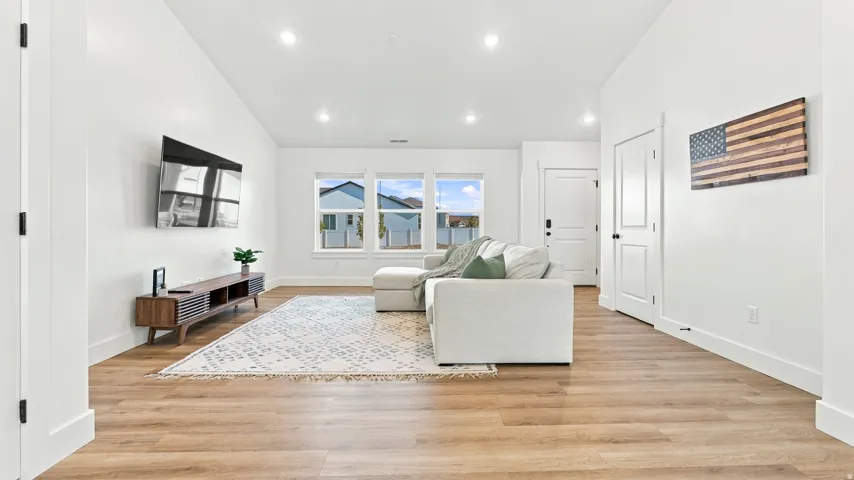 Brightly lit interior space featuring light wood-finish flooring, white walls, and recessed lighting