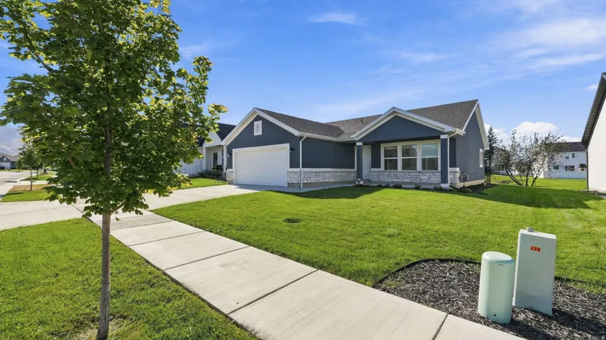Contemporary ranch-style residence featuring a dark blue facade with white trim, a stone-accented foundation, and an attached two-car garage