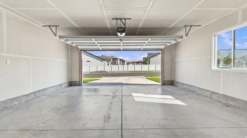 Attached garage with a concrete floor, automatic garage door opener, and a single window