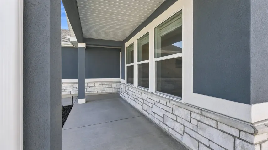 Covered concrete porch with textured stucco siding and a stacked stone facade