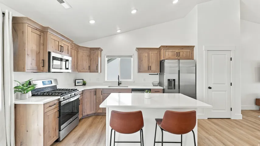 Kitchen featuring wood-finish cabinetry, stainless steel appliances, white countertops, and a center island