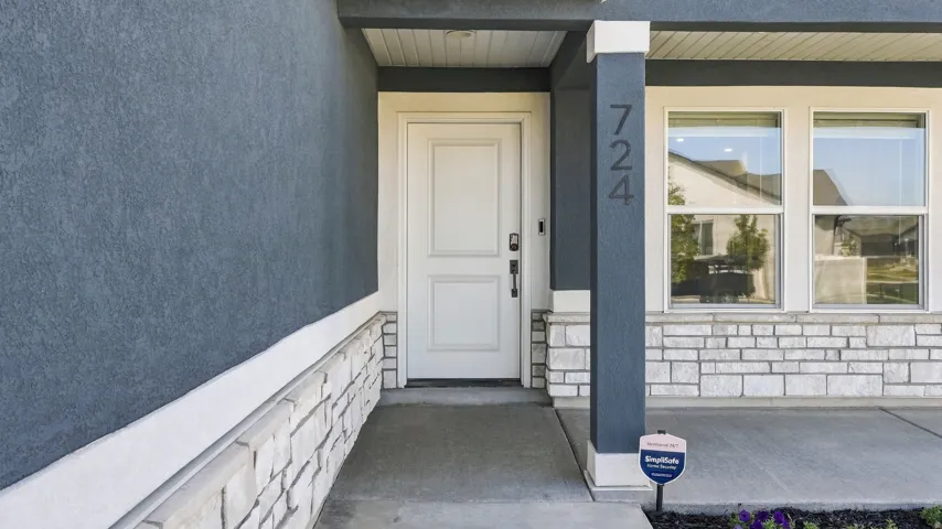 Stucco exterior with stone veneer accents, a paneled entry door, and double-hung windows