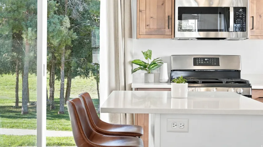 Sliding glass door, stainless steel microwave, stainless steel range, light-toned cabinetry, light-toned countertops