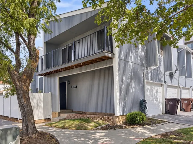 Two-story townhouse with vertical siding, a second-story balcony with dark railings, and an attached garage