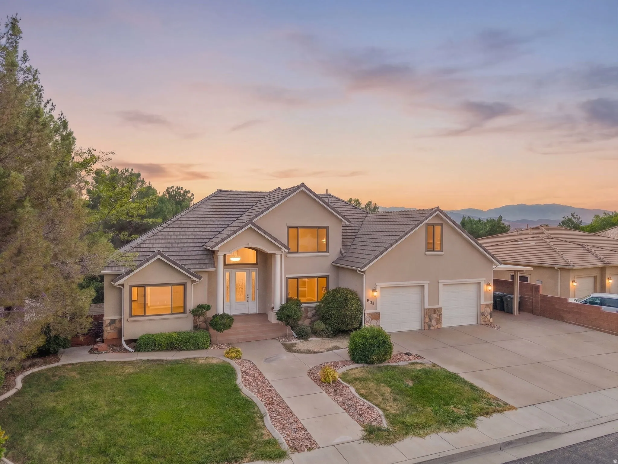 Stucco exterior with stone accents, tile roof, and an attached two-car garage