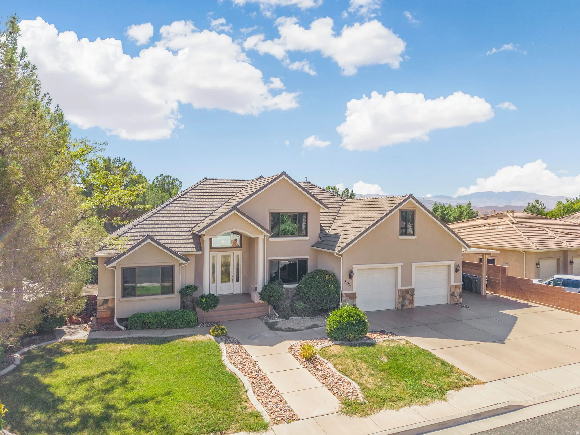 Stucco exterior with a tile roof, two-car garage, and a concrete driveway