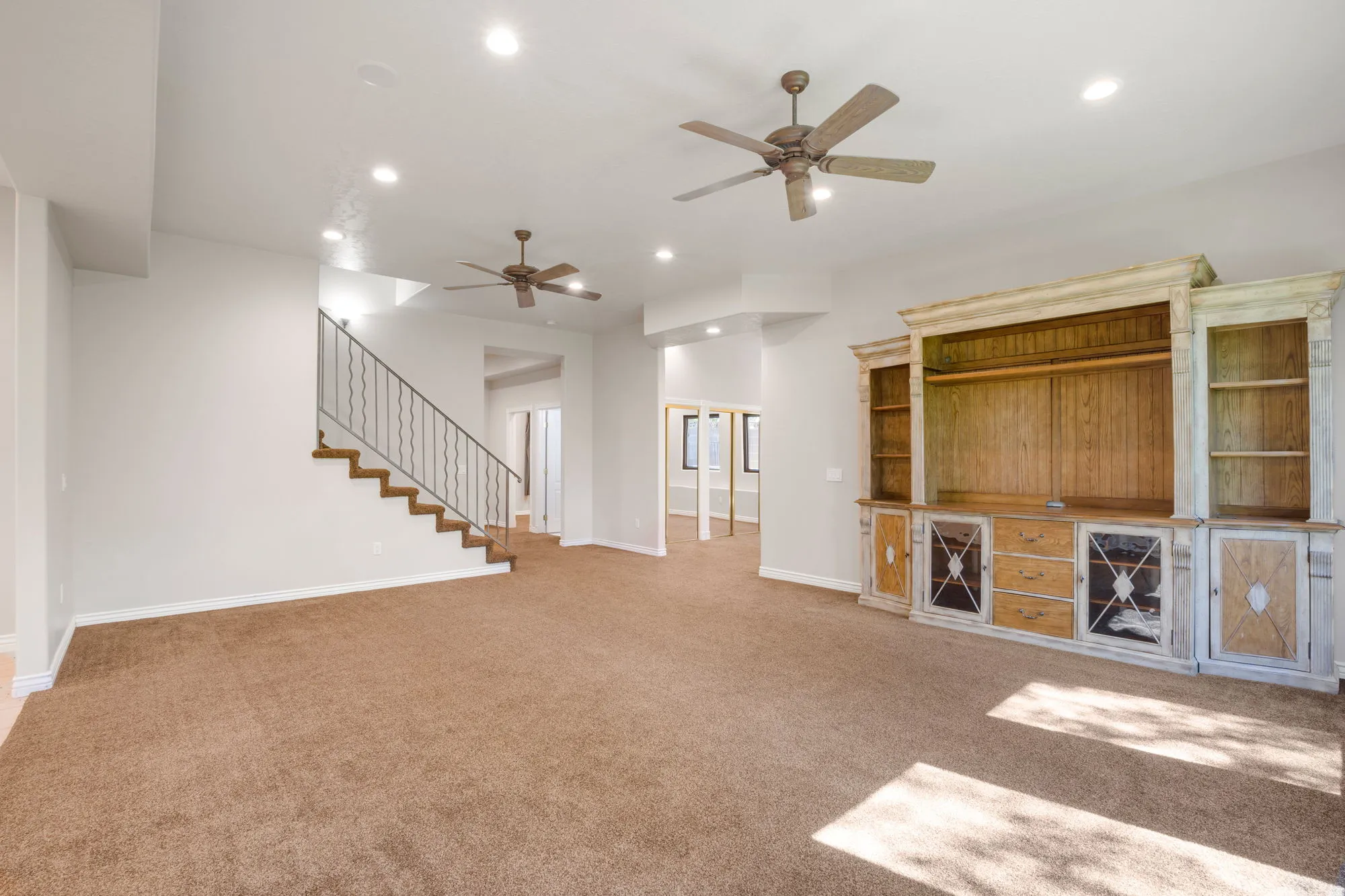 Carpeted living space featuring recessed lighting, two ceiling fans, and a built-in entertainment center
