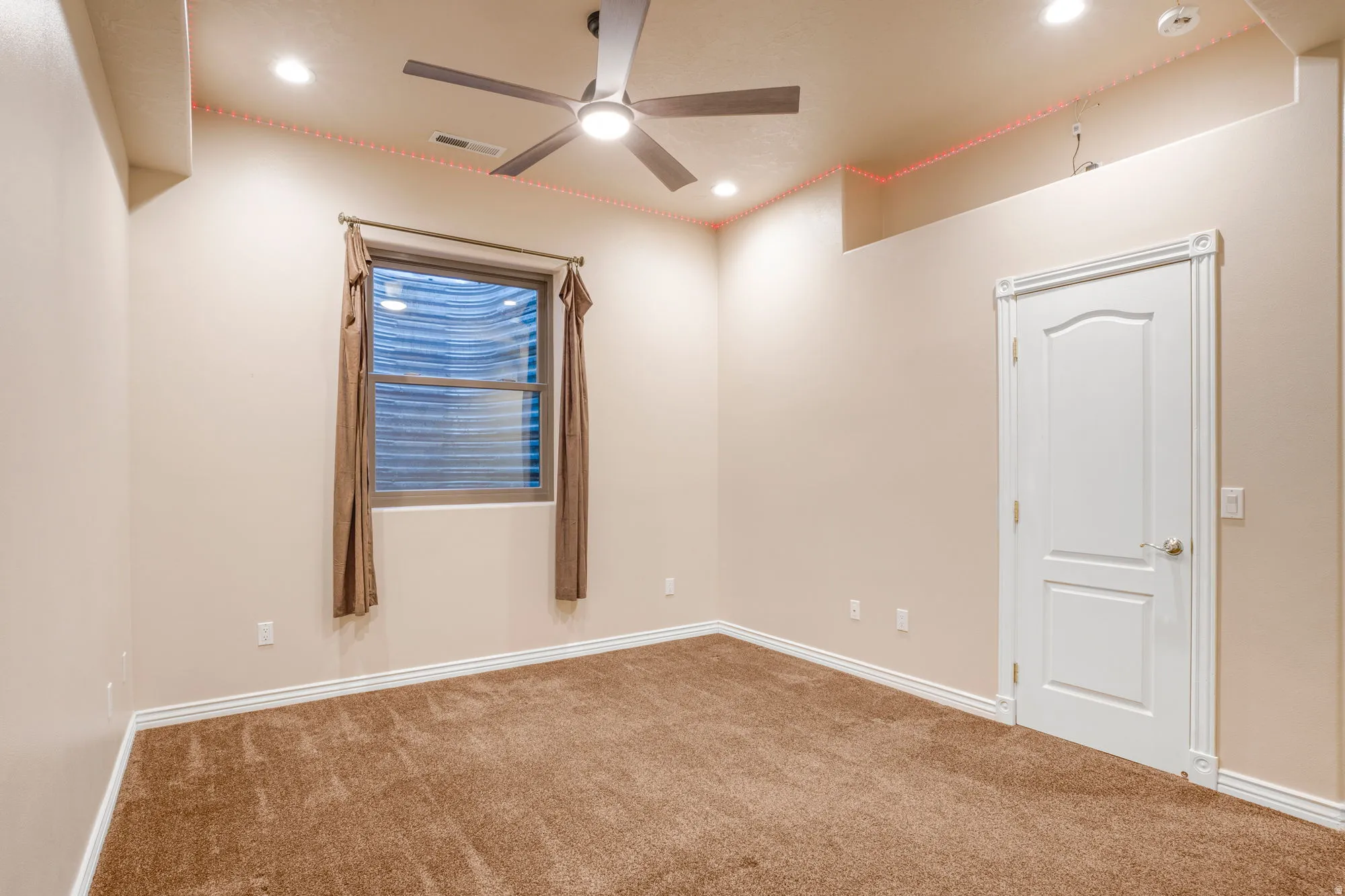 Recessed lighting, ceiling fan, neutral carpeting, window with privacy blinds, and a paneled interior door