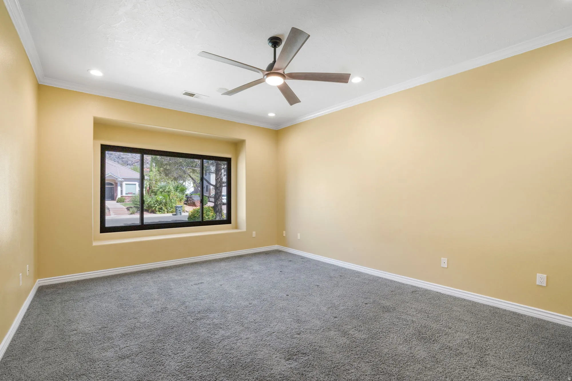 Recessed window with black framing, gray carpet, crown molding, modern ceiling fan, and recessed lighting