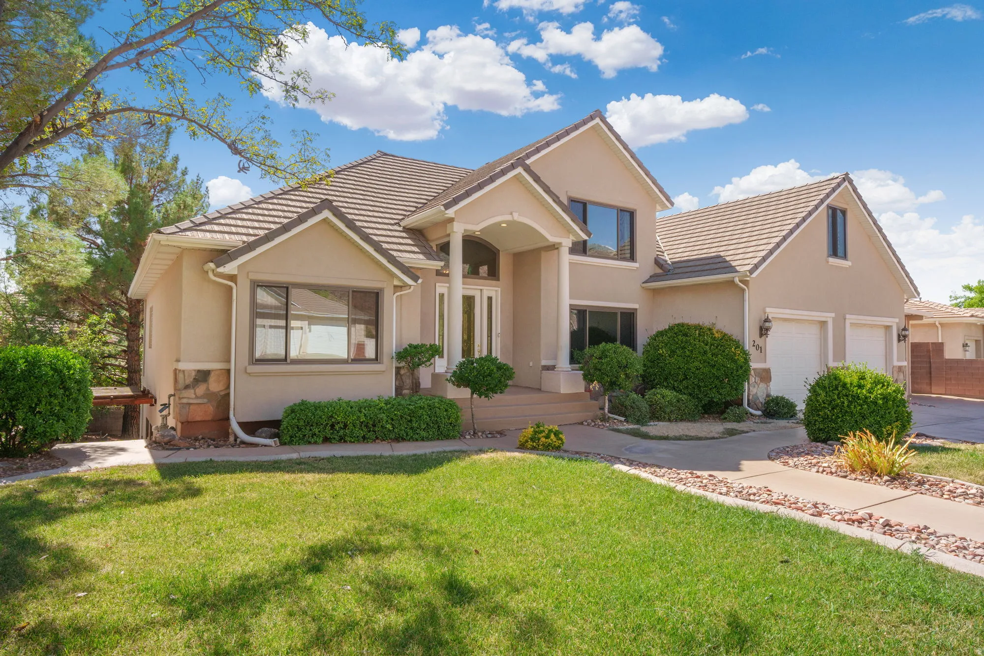 Stucco exterior with stone accents, tile roofing, and an integrated two-car garage