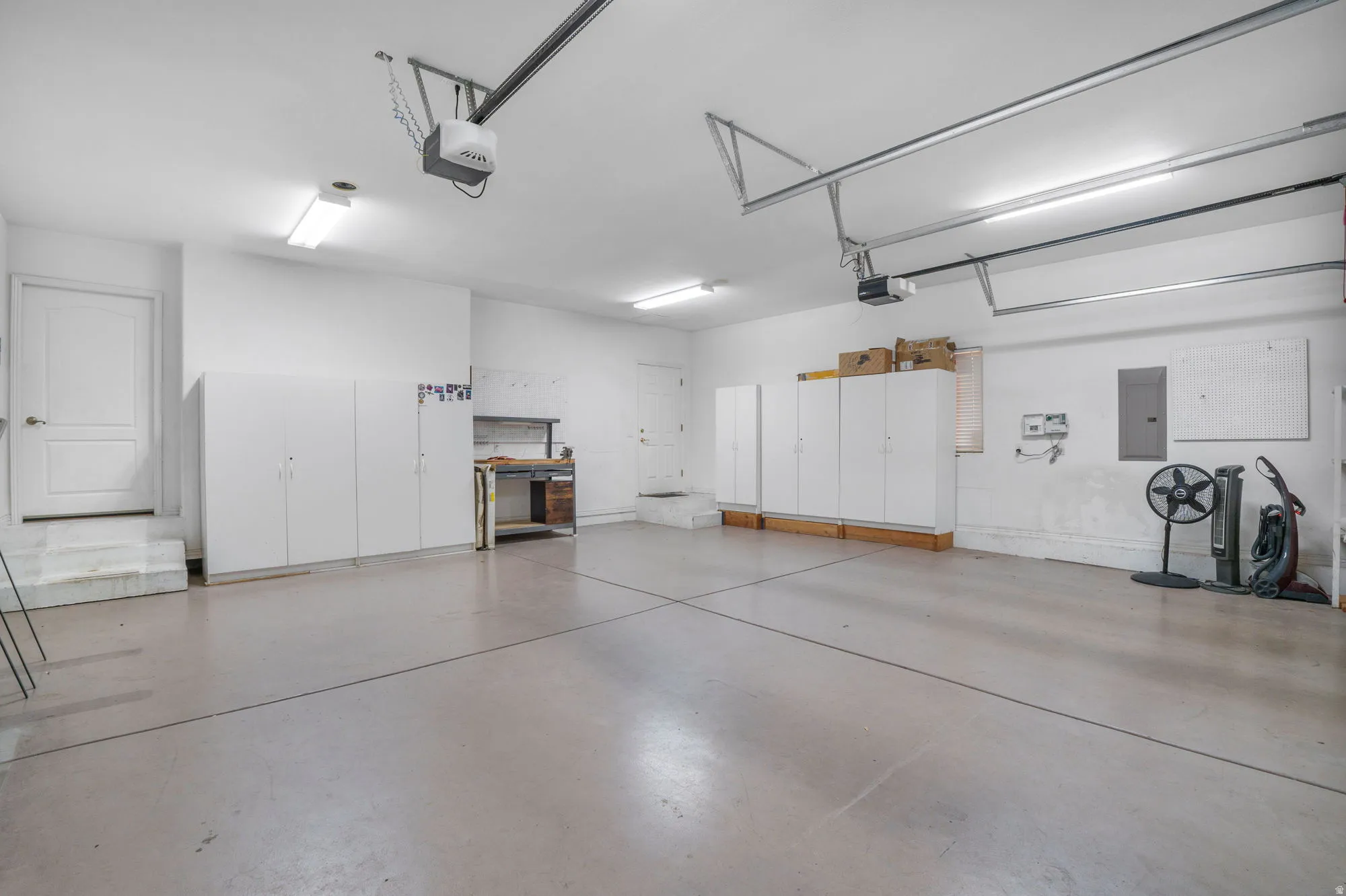 Expansive garage with a light gray concrete floor and multiple fluorescent light fixtures