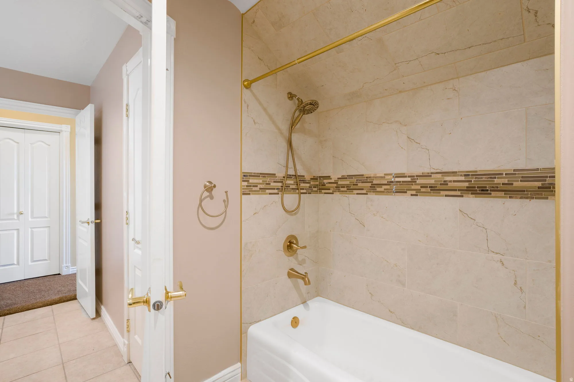 Tub and shower combination with a decorative tile surround and an accent mosaic tile band