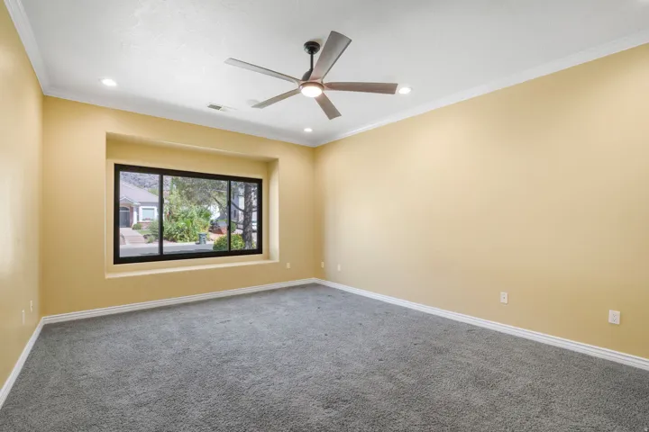 Recessed window with black framing, gray carpet, crown molding, modern ceiling fan, and recessed lighting
