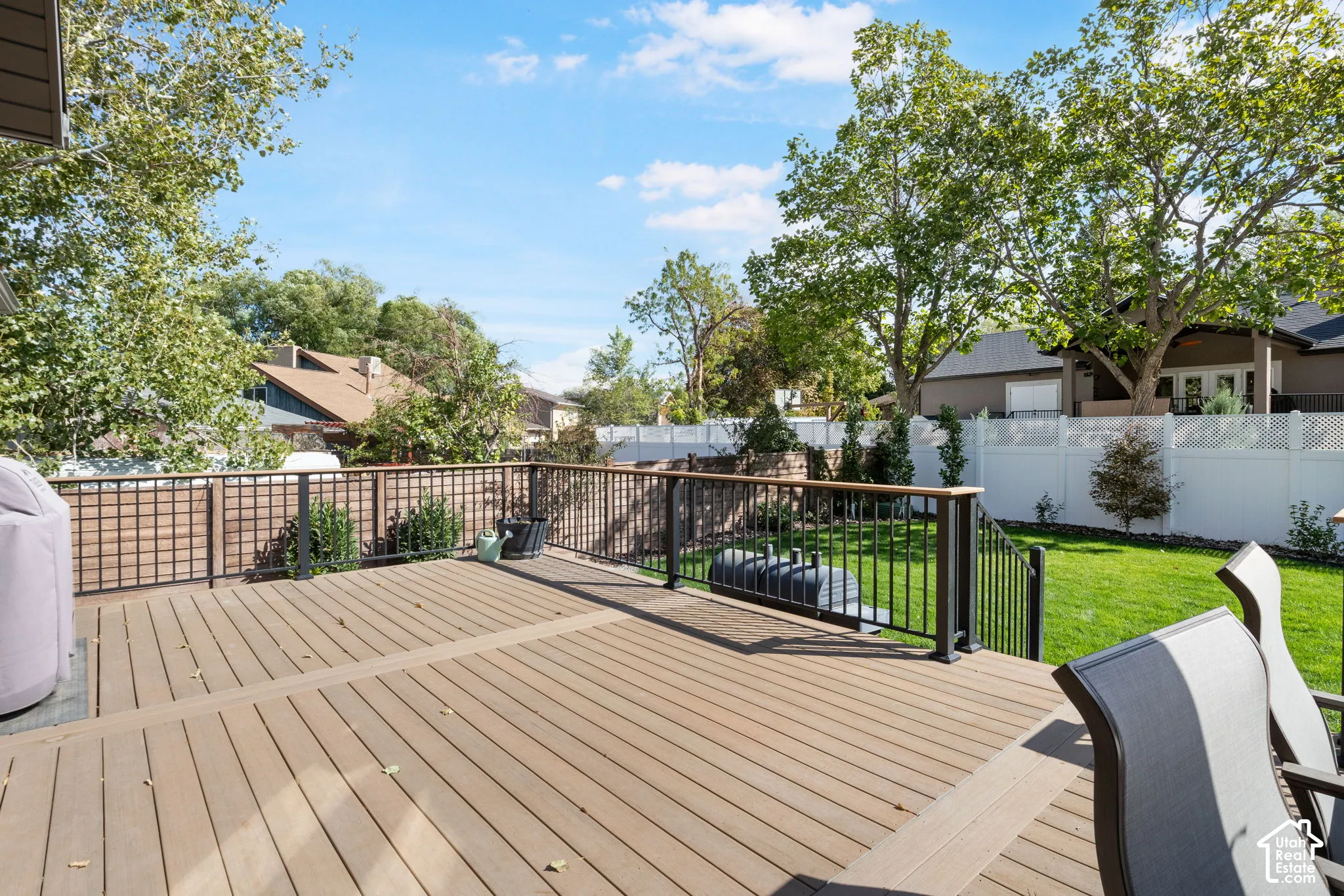 Expansive composite deck with dark metal railings, leading to a vibrant green lawn