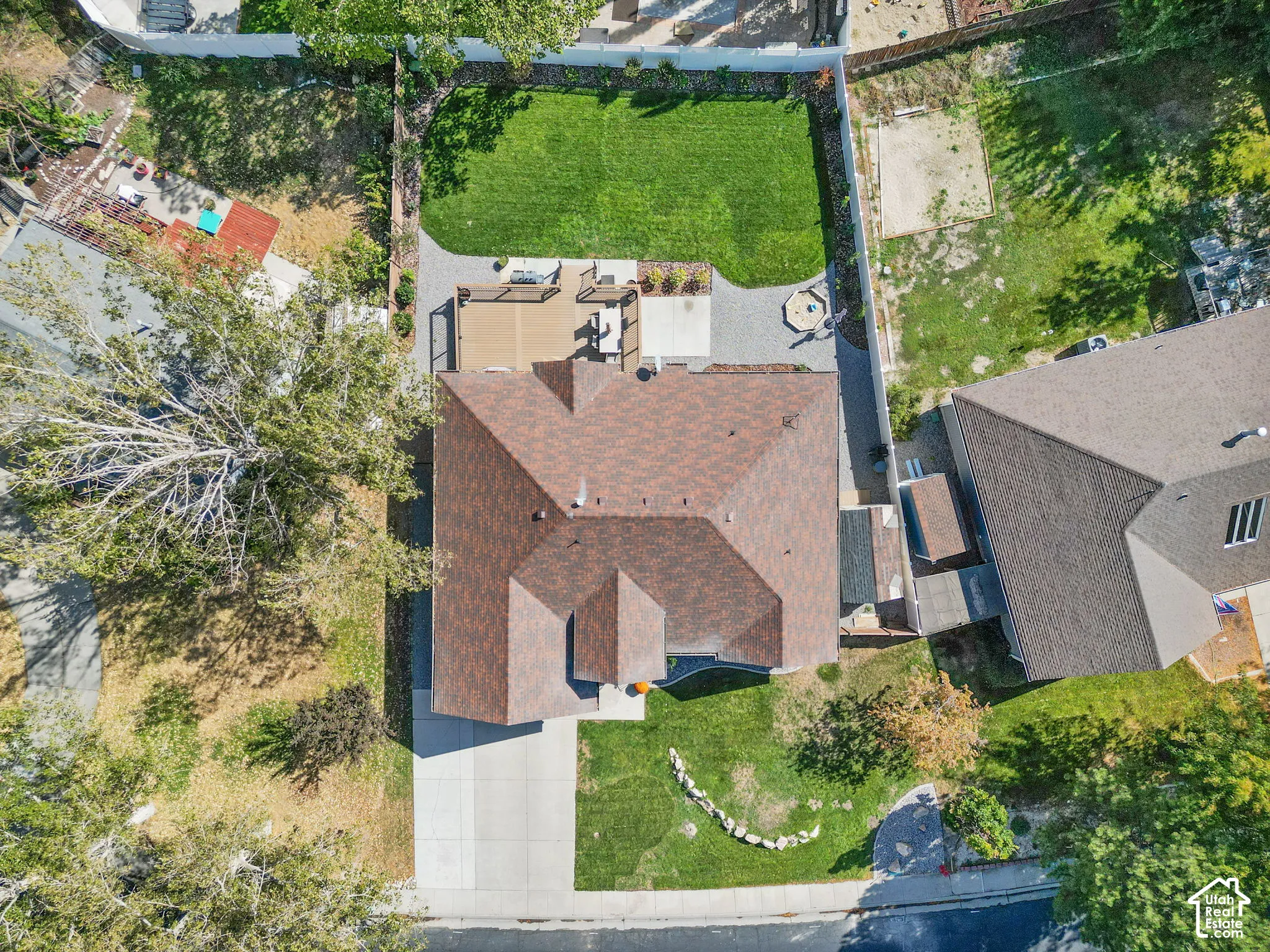 Expansive backyard featuring a manicured lawn, a built-in fire pit area, a large composite deck, and a paved patio