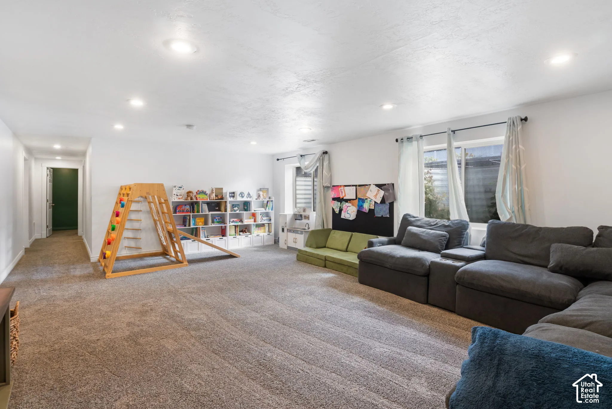 Recessed lighting illuminates the carpeted flooring and white walls