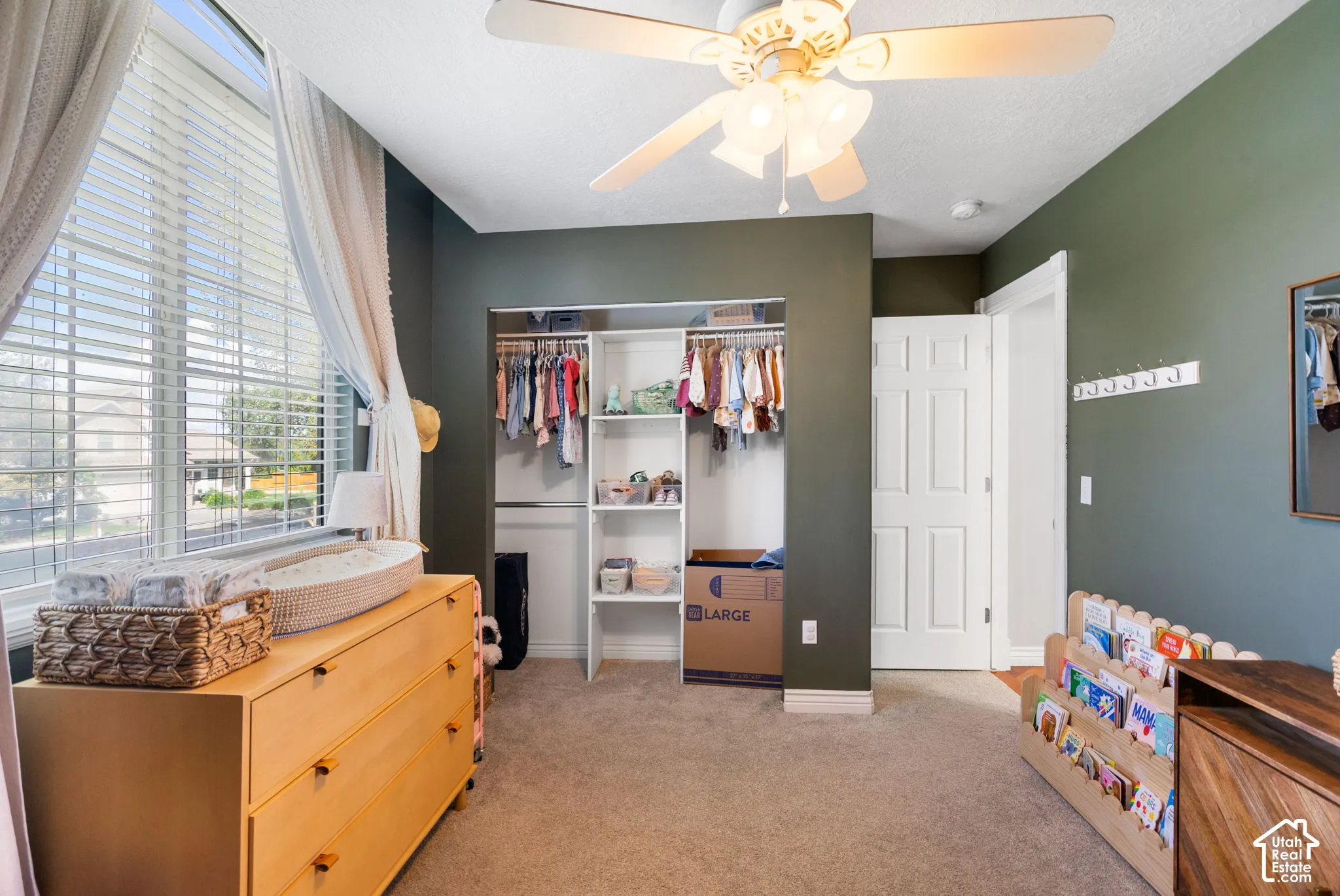 Recessed open closet with shelving, ceiling fan with light fixture, carpeted flooring, large window with blinds, and paneled interior door