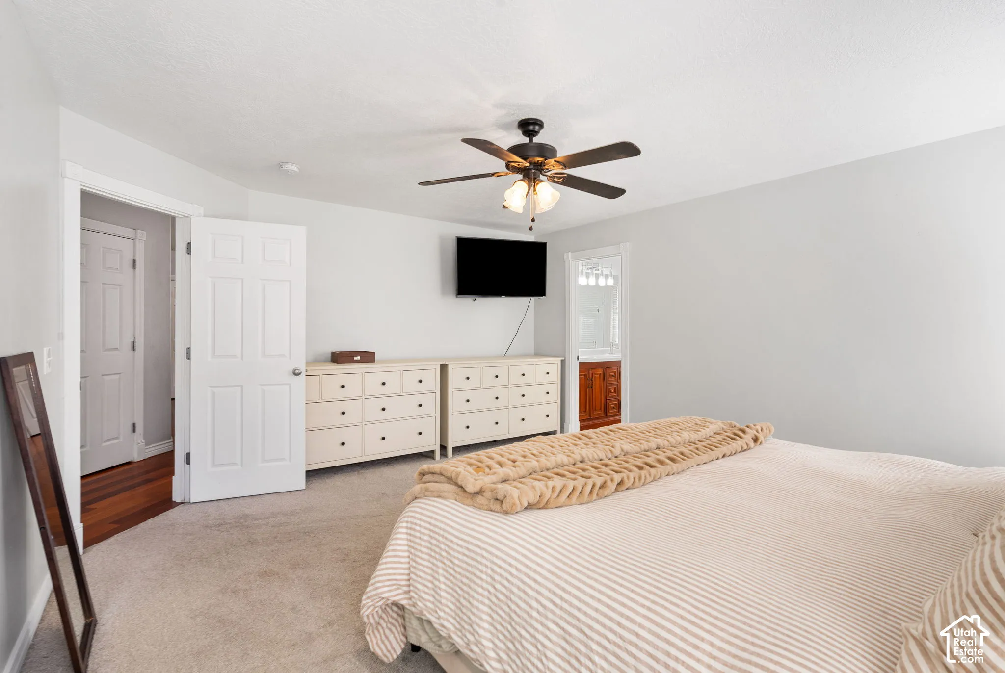 Light-colored carpeting with a ceiling fan and overhead lighting